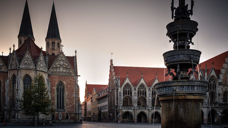 A historic church with twin spires and a Gothic-style fountain in the foreground.