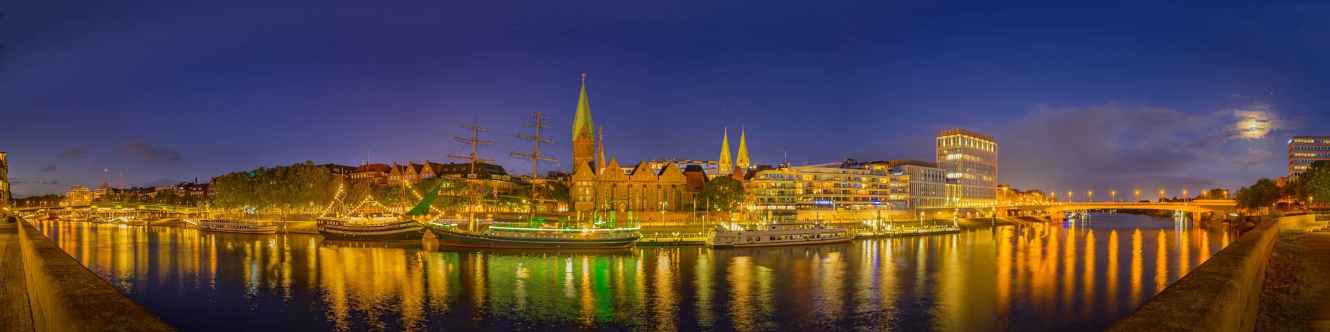 A river with boats, a bridge, and historic buildings at night.
