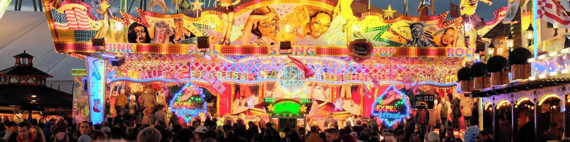 A brightly lit amusement park with a large sign reading "MUSIK EXPRESS" and a roller coaster in the background.
