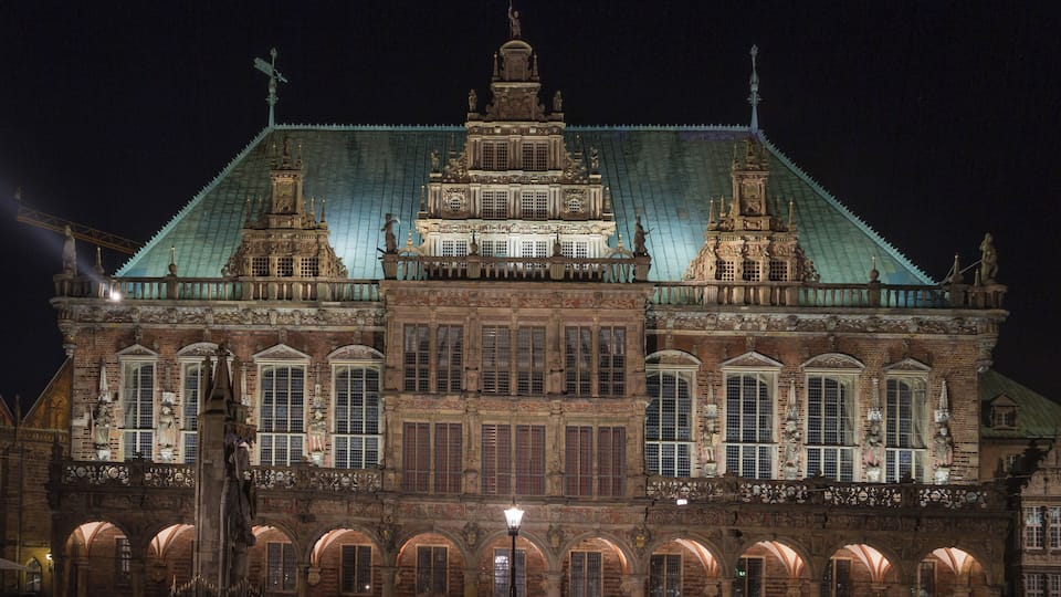 A historic building with intricate architecture, a large central dome, and a statue on the roof.