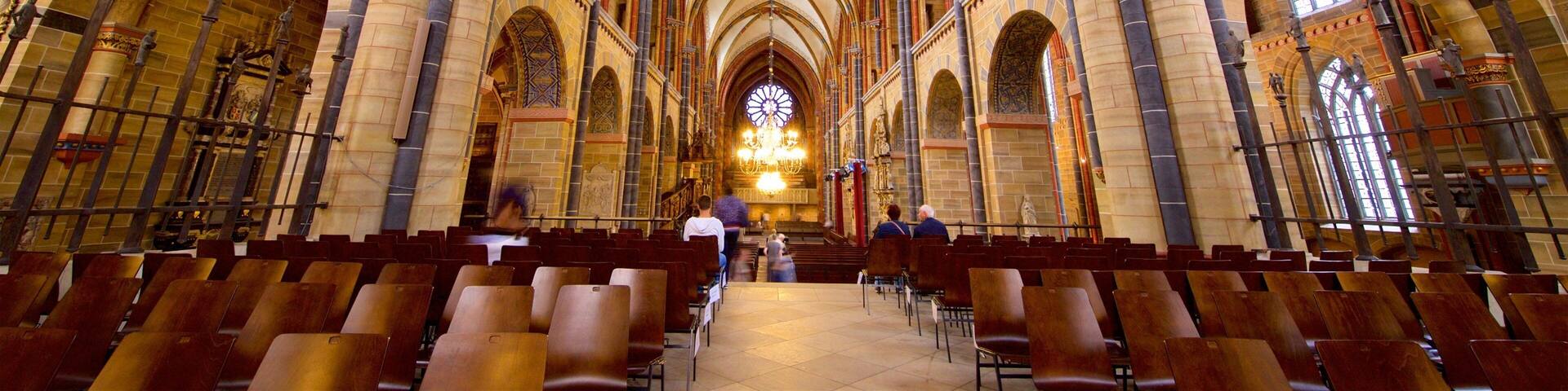 A cathedral interior with high vaulted ceilings, ornate columns, and a large chandelier.
