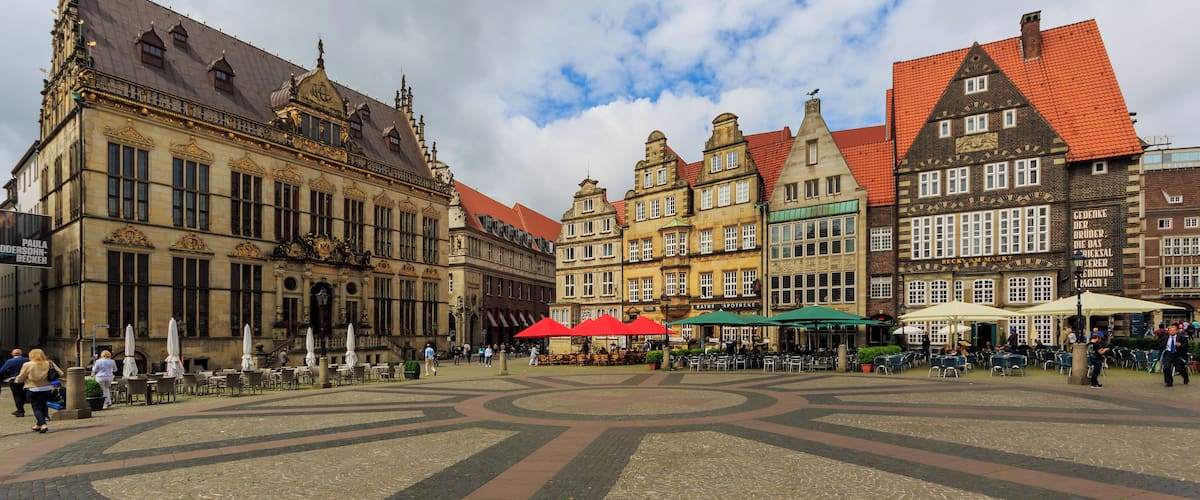 A historic square with ornate buildings, outdoor cafes, and cobblestone pavement.