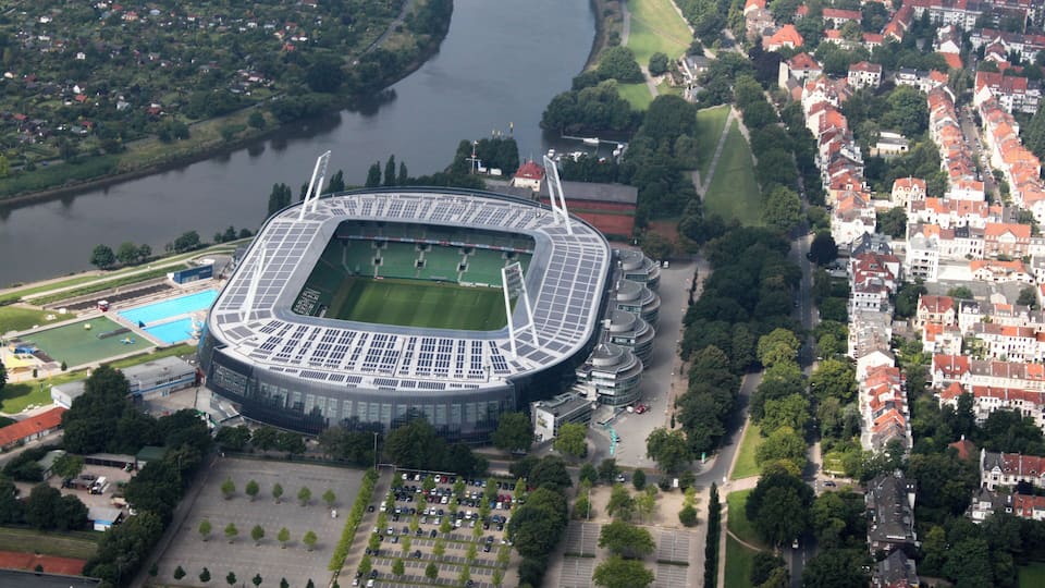 An aerial view of a stadium surrounded by a river and residential buildings.