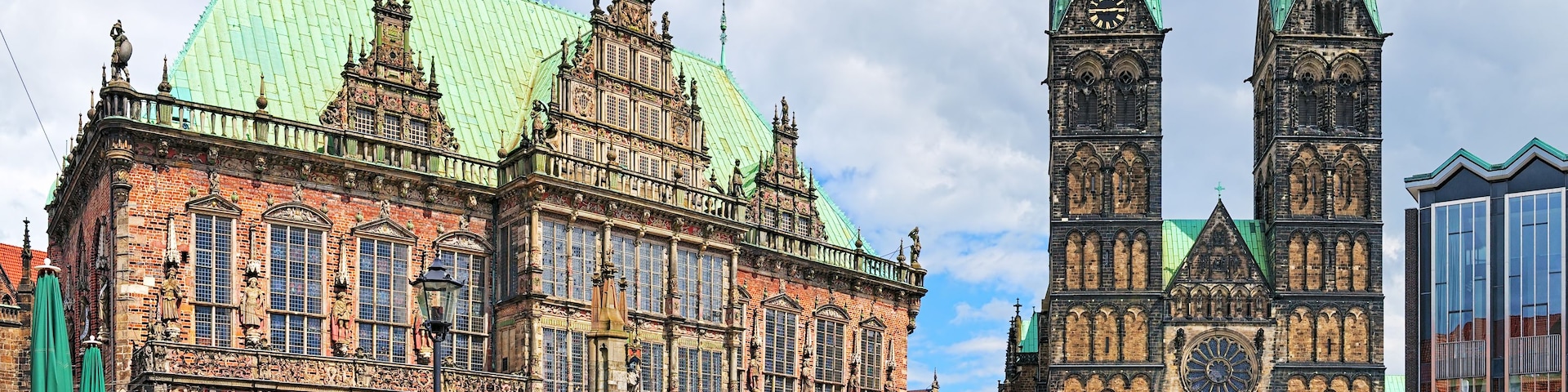 Ein historisches Gebäude mit aufwendiger Architektur, einem hohen Glockenturm und einem Gebäude mit Gründach.