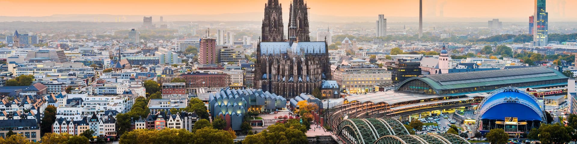 A cityscape with a prominent cathedral, modern buildings, and a large stadium.