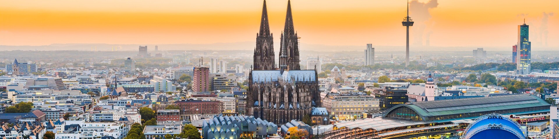 Paisagem urbana com uma catedral imponente, edifícios modernos e um grande estádio.