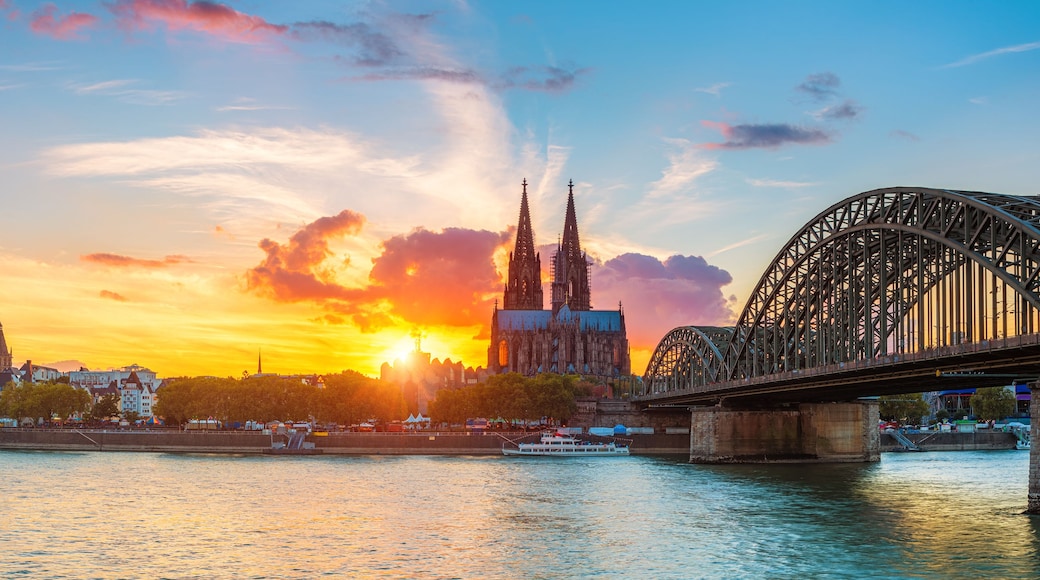 A sunset over a city with two prominent cathedrals and a large bridge.