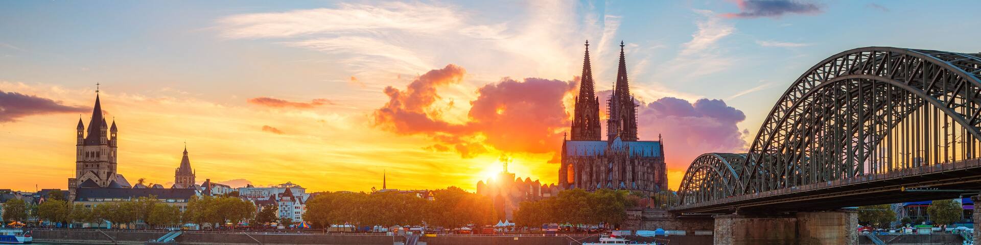 A sunset over a city with two prominent cathedrals and a large bridge.