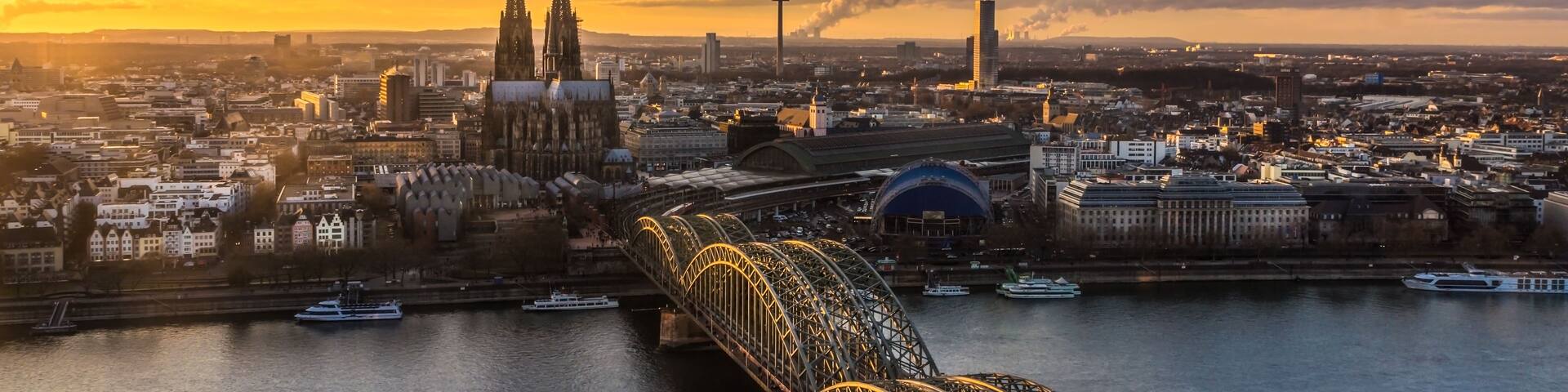 A cityscape with a prominent cathedral, a tower, and a bridge with illuminated cables.