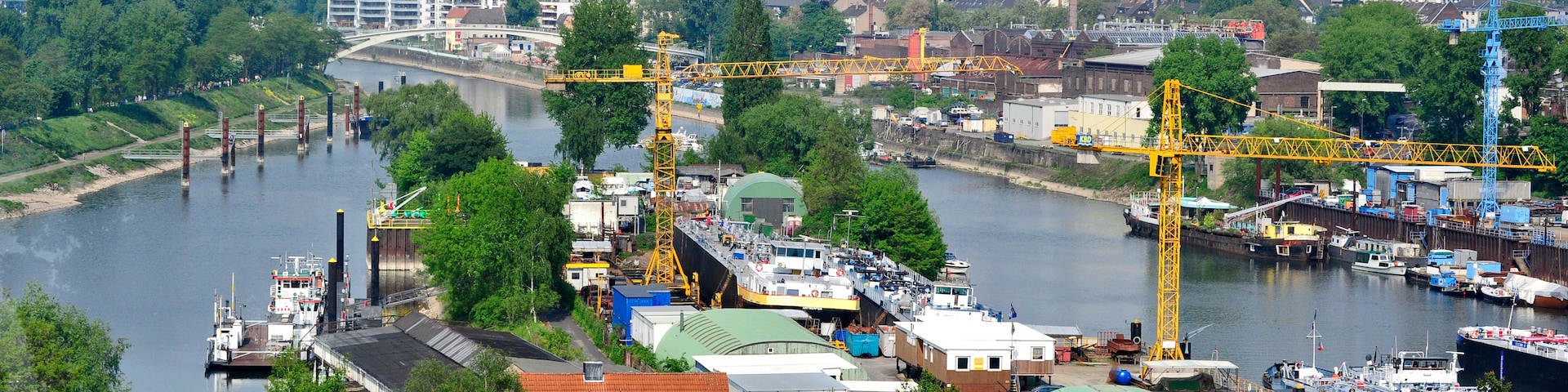 A river with boats, a bridge, and industrial cranes.