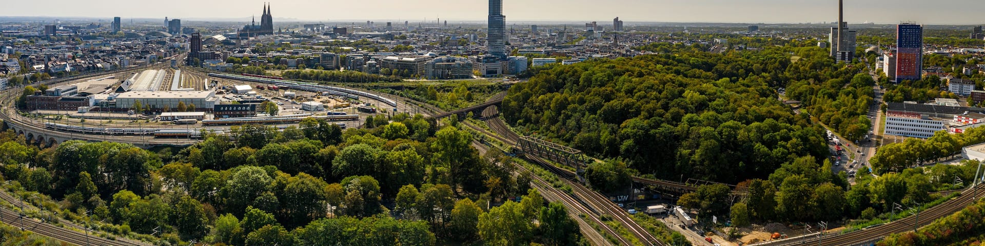 A cityscape with a prominent tower, dense greenery, and a complex railway network.