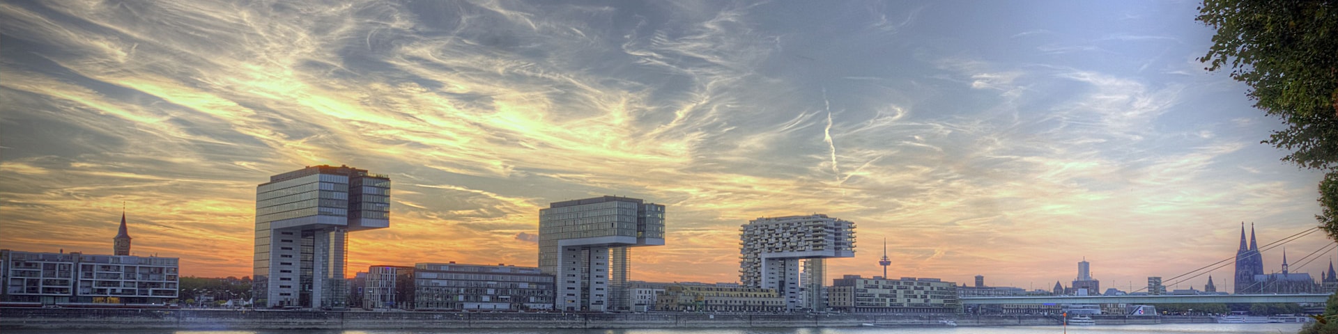 Eine Stadtansicht mit moderner Architektur, einem Fluss und einem Sonnenuntergangshimmel.