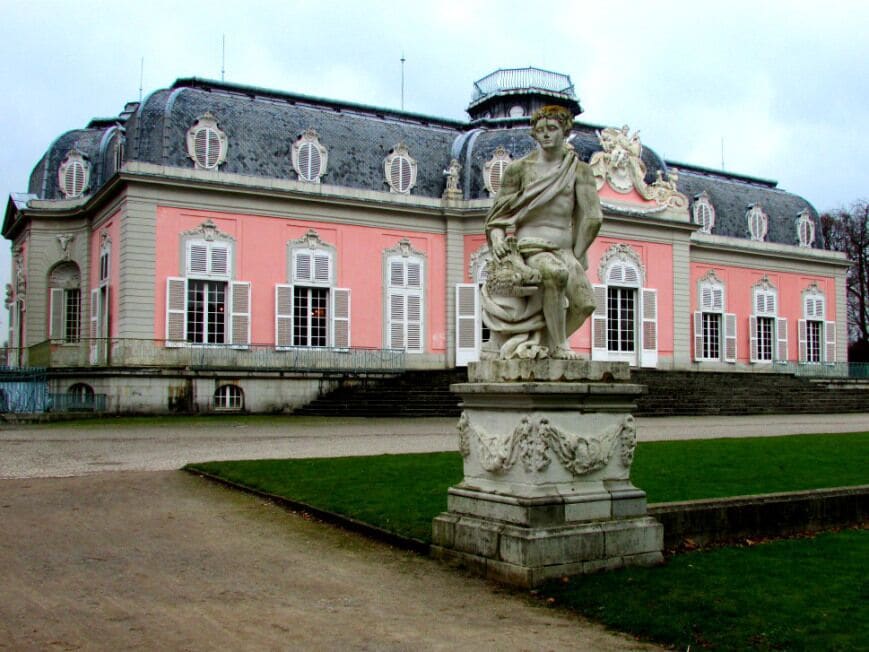 A pink building with a statue in front.