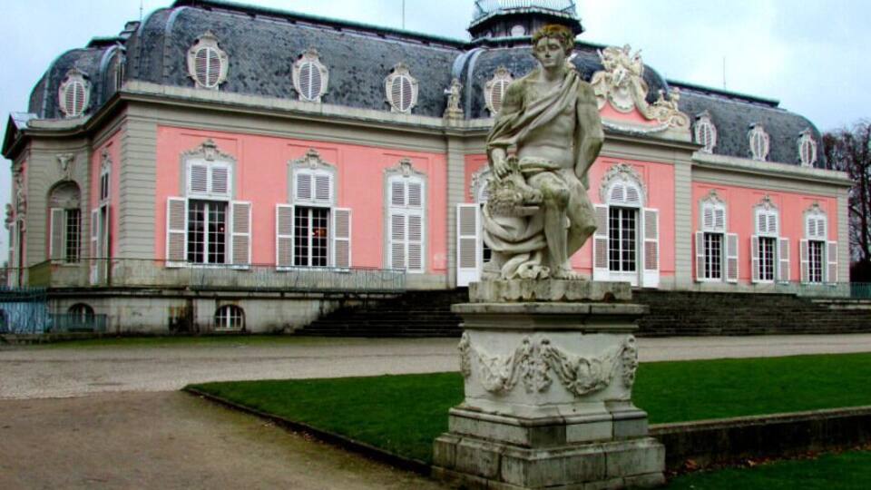 A pink building with a statue in front.