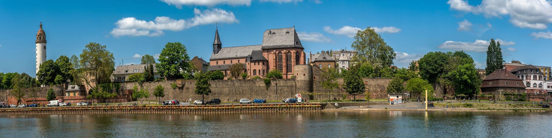 A historic cityscape with a prominent church, a tower, and a river.