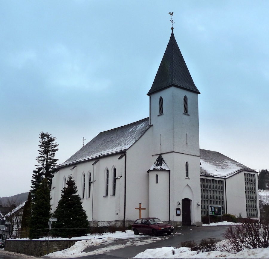 A white church with a tall steeple and a cross on the front.