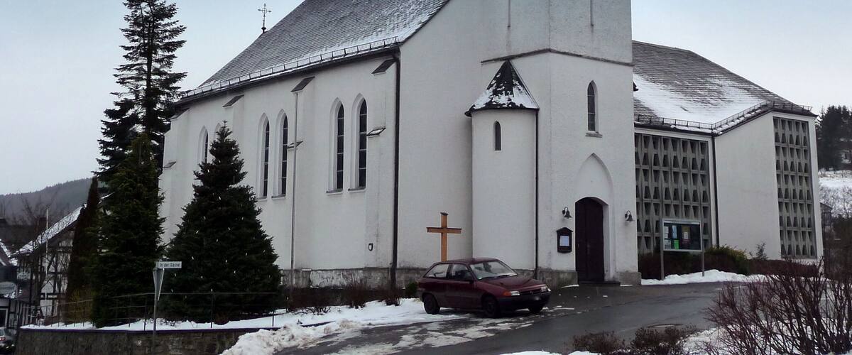 A white church with a tall steeple and a cross on the front.