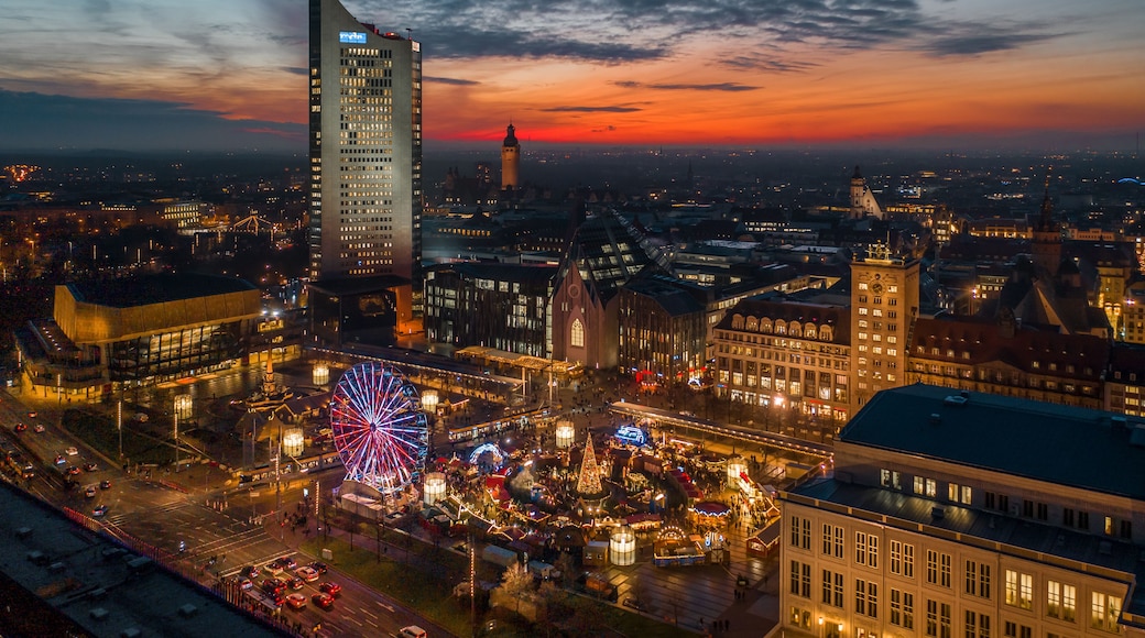 A cityscape at dusk with illuminated buildings, a Ferris wheel, and a prominent tower.