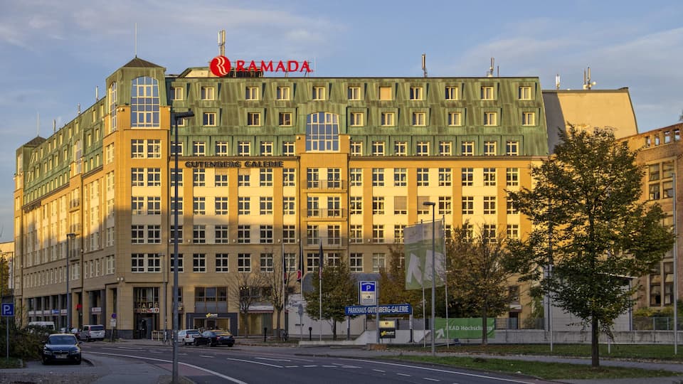 A multi-story building with a green facade and a sign reading "RAMADA."