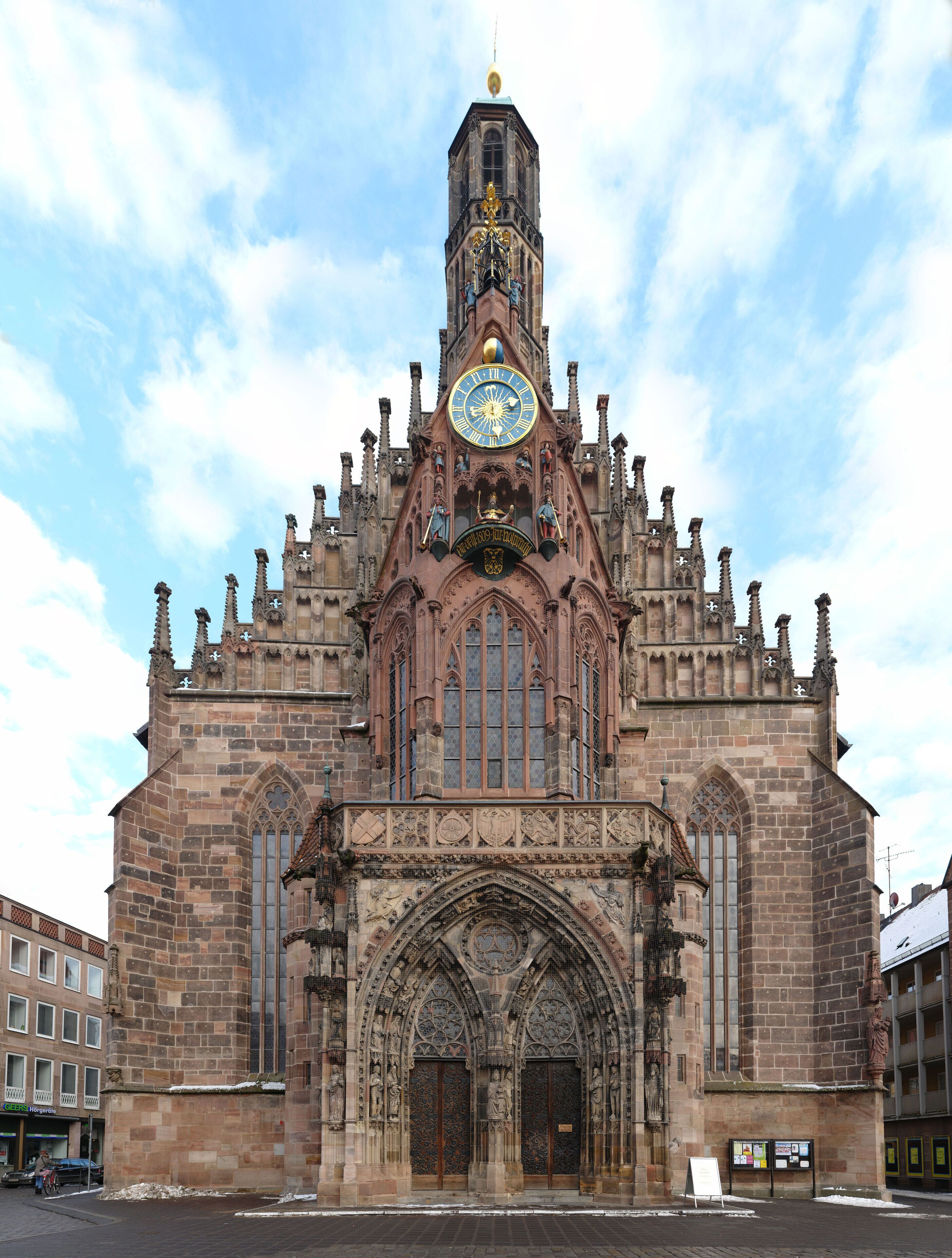 Una catedral històrica amb arquitectura gòtica detallada, una torre del rellotge destacada i ornaments de pedra minuciosos.
