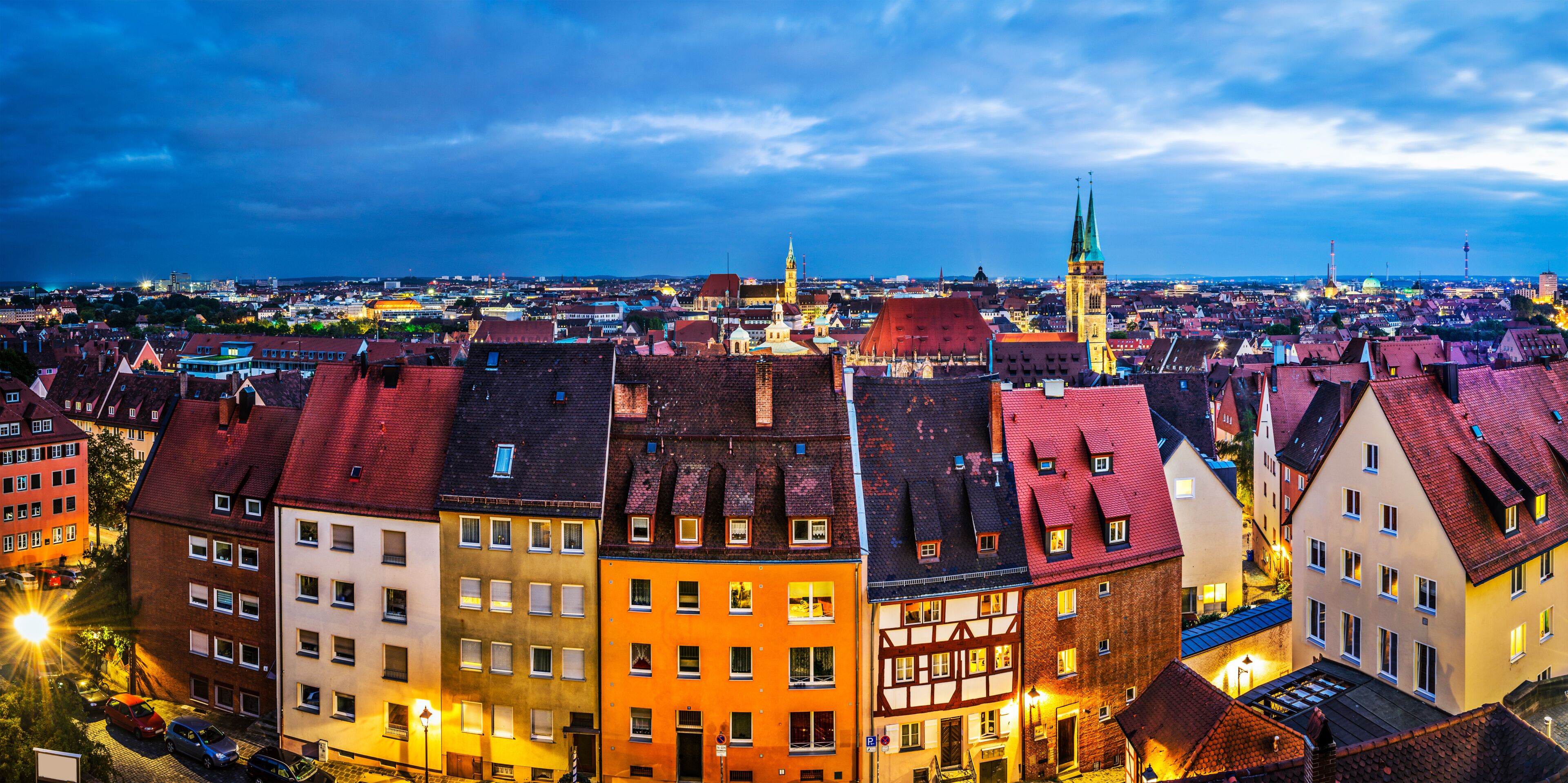 A cityscape with historic buildings, a prominent church tower, and a cathedral with a green spire.