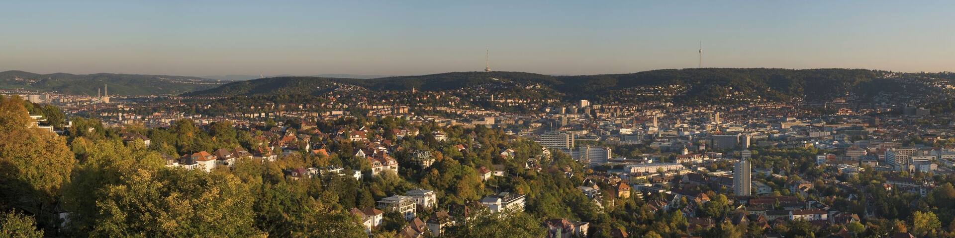 A cityscape with a dense urban area surrounded by hills and trees.