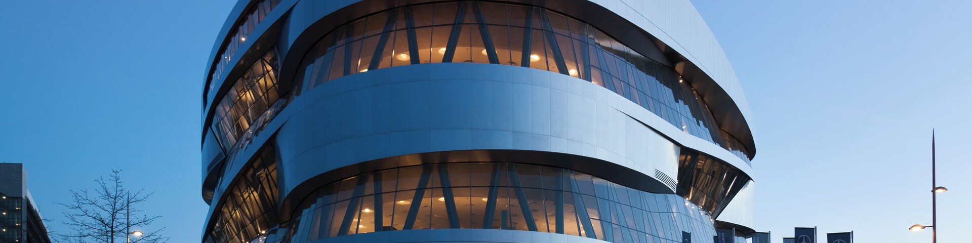 El Museo Mercedes-Benz, con una arquitectura moderna y curvas, y ventanas iluminadas.