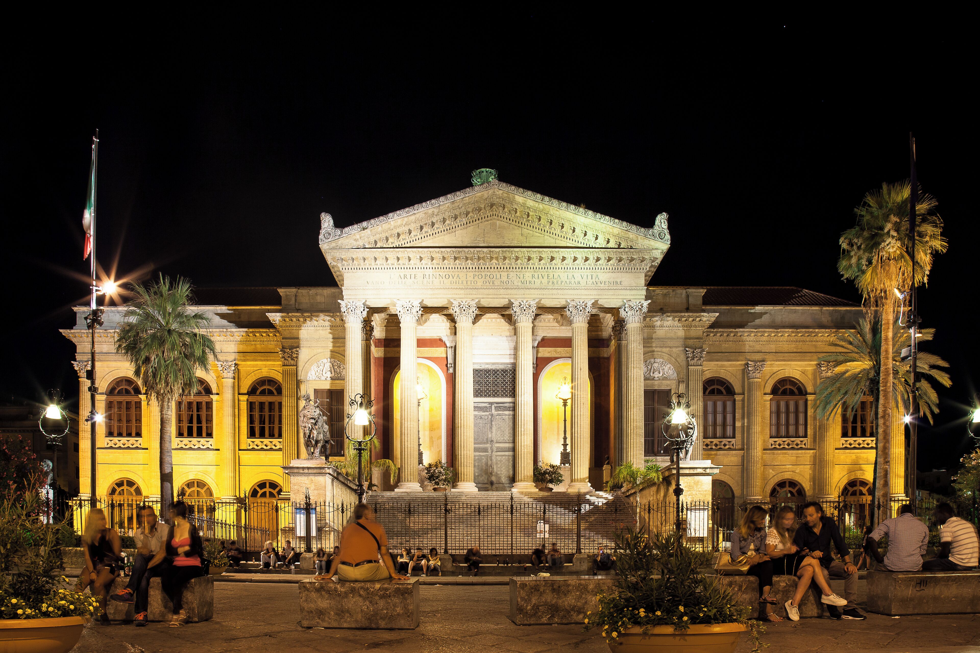 A grand neoclassical building with columns and a central pediment, illuminated at night.