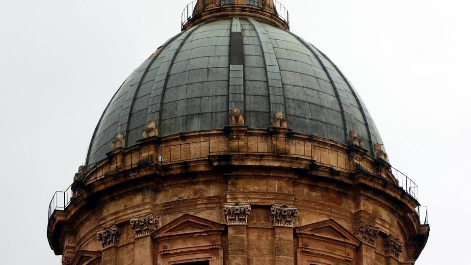 A large domed building with a cross on top, featuring arched windows and intricate stonework.