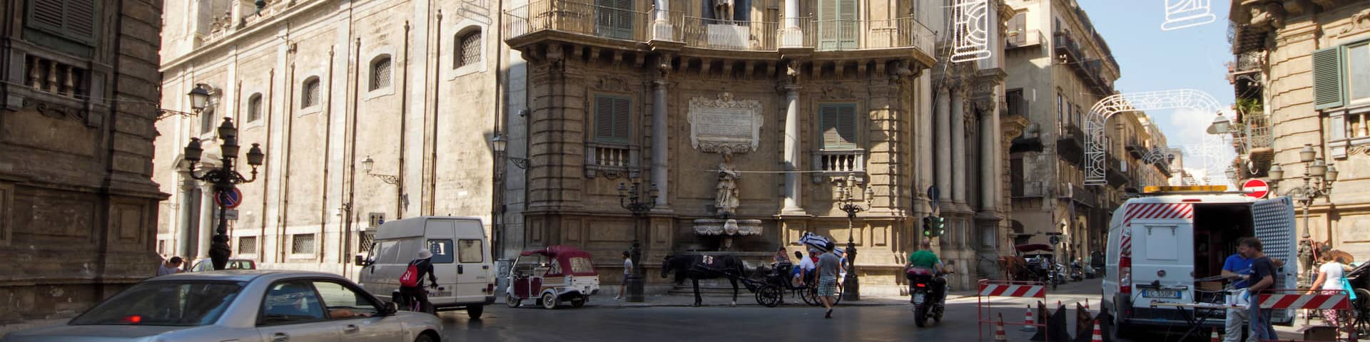 A historic building with ornate architecture, a horse-drawn carriage, and a busy street with vehicles and pedestrians.