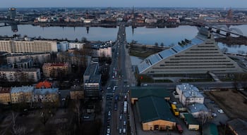 Aerial view of the National Library of Latvia and the Akmens tilts bridge spanning the Daugava River towards the historic Old Riga skyline at sunset, Riga, Latvia.
