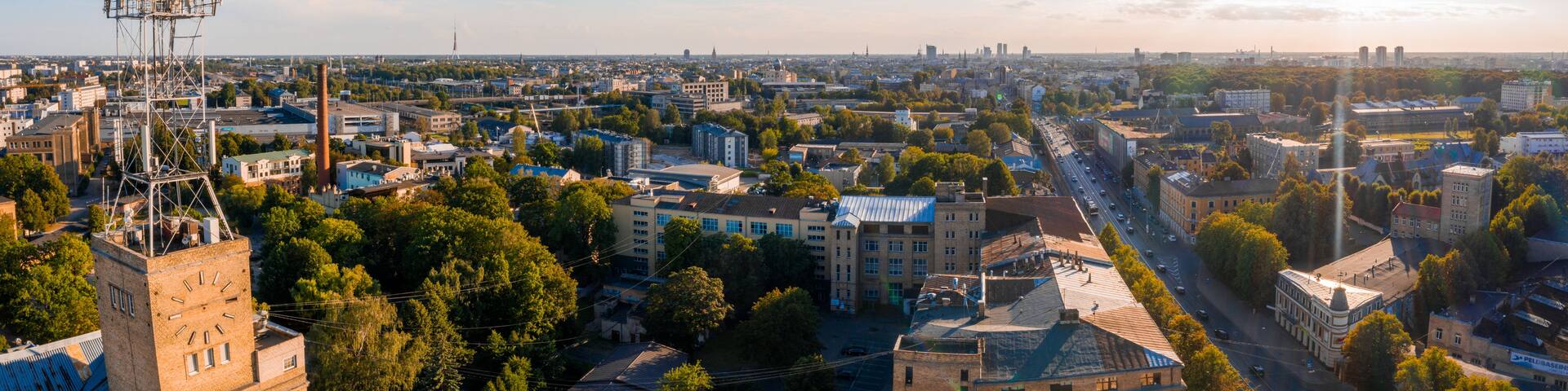 A cityscape with a prominent clock tower, dense urban buildings, and a clear sky.