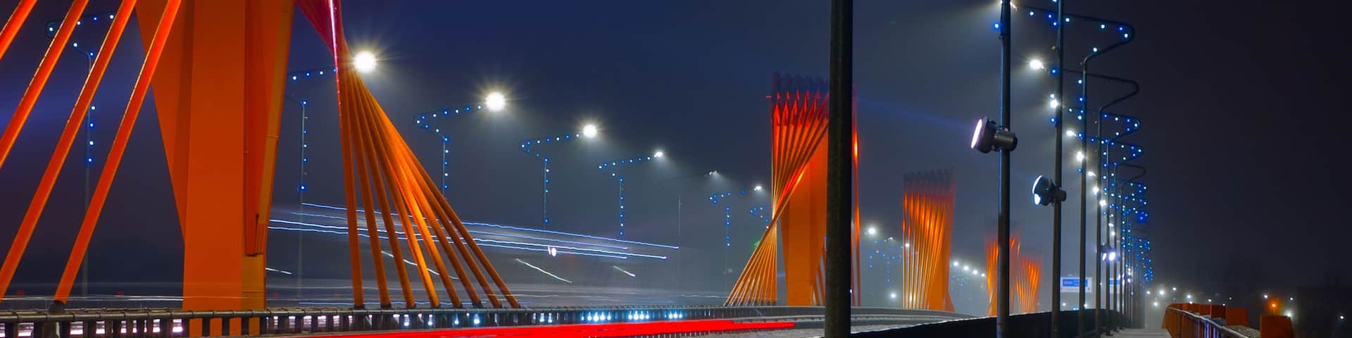 A bridge at night with illuminated red and blue lights.