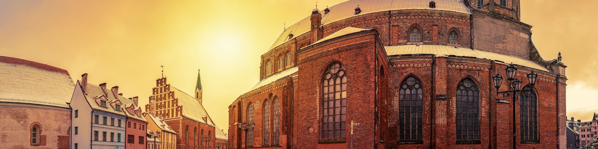 Una iglesia histórica con una cúpula y un campanario, rodeada de calles cubiertas de nieve y edificios tradicionales.