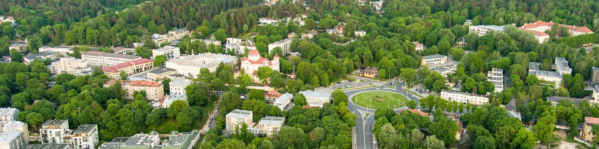 A river with a bridge, surrounded by dense forests and a mix of residential and commercial buildings.