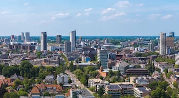 Aerial view of Eindhoven, Netherlands, showing the Evoluon, Philips Stadium, modern buildings, traditional architecture, and green spaces under a clear sky.