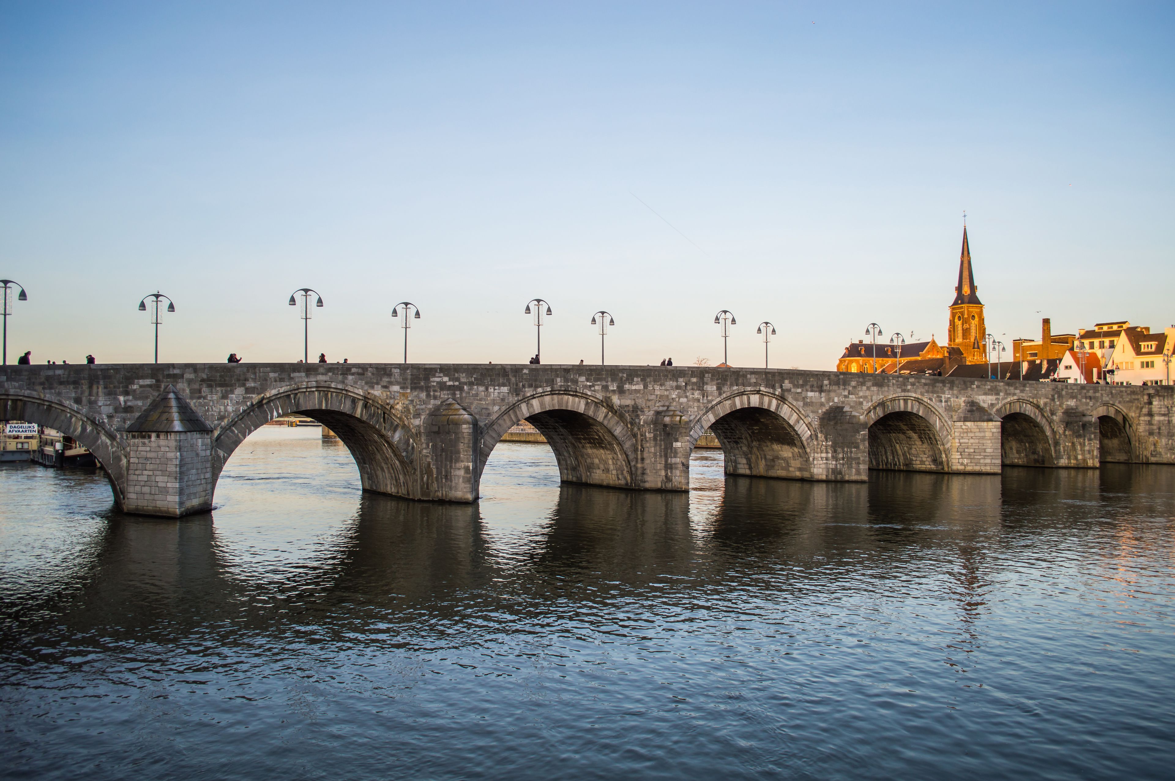 Eine Stebrücke über Wasser, im Hintergrund eine Kirche.
