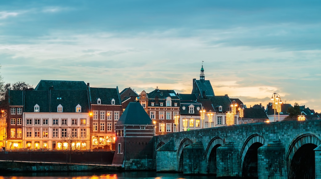 Eine historische Brücke mit mehreren Bögen über einem Fluss, der Stadtlichter reflektiert.