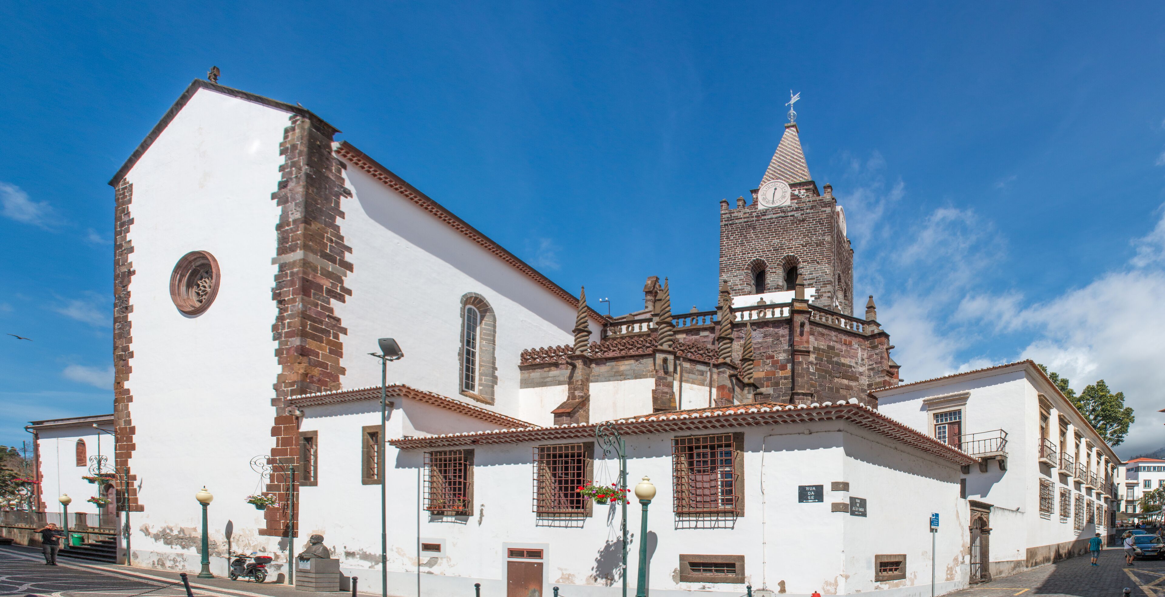 A historic church with a bell tower and a statue in front.