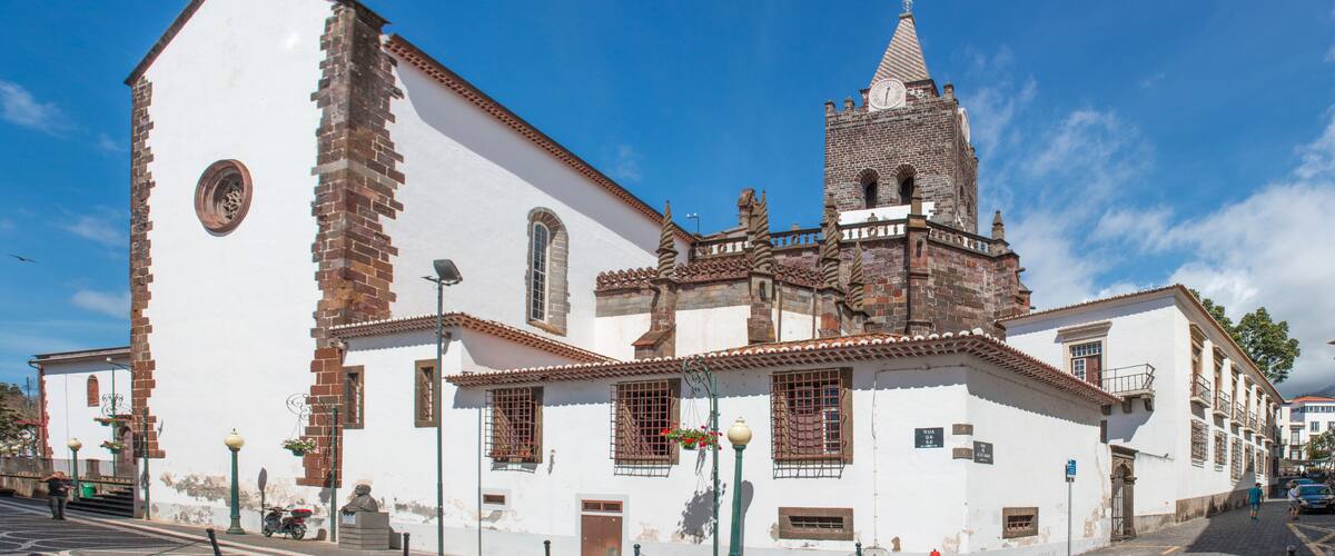 A historic church with a bell tower and a statue in front.