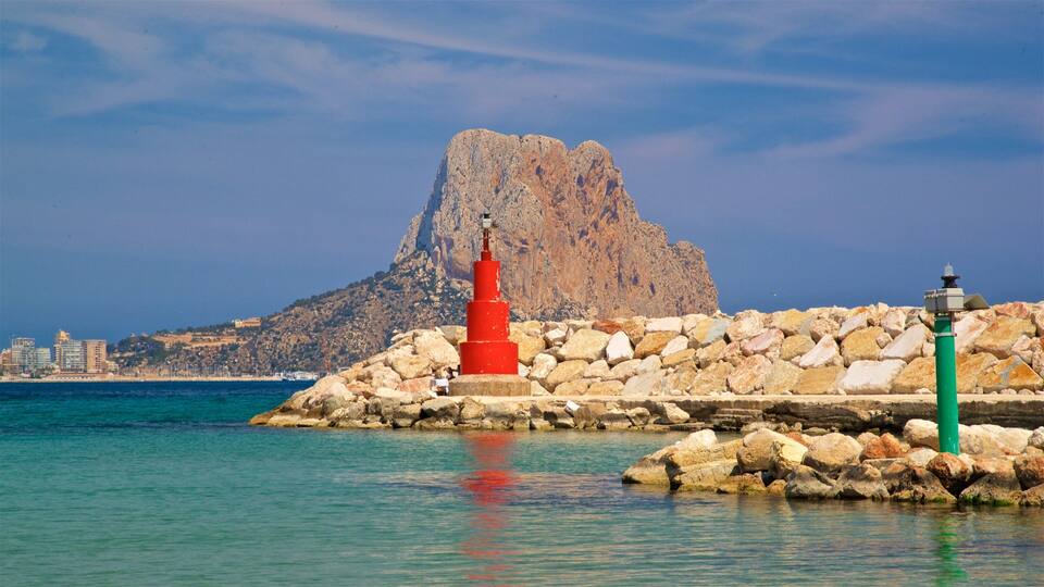 A coastal scene with a red lighthouse, a green lighthouse, and a rocky outcrop with a mountain in the background.