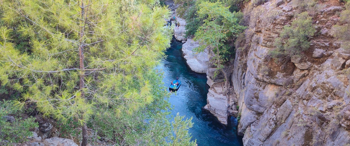 A river flowing through a canyon with rocky cliffs and dense green foliage.