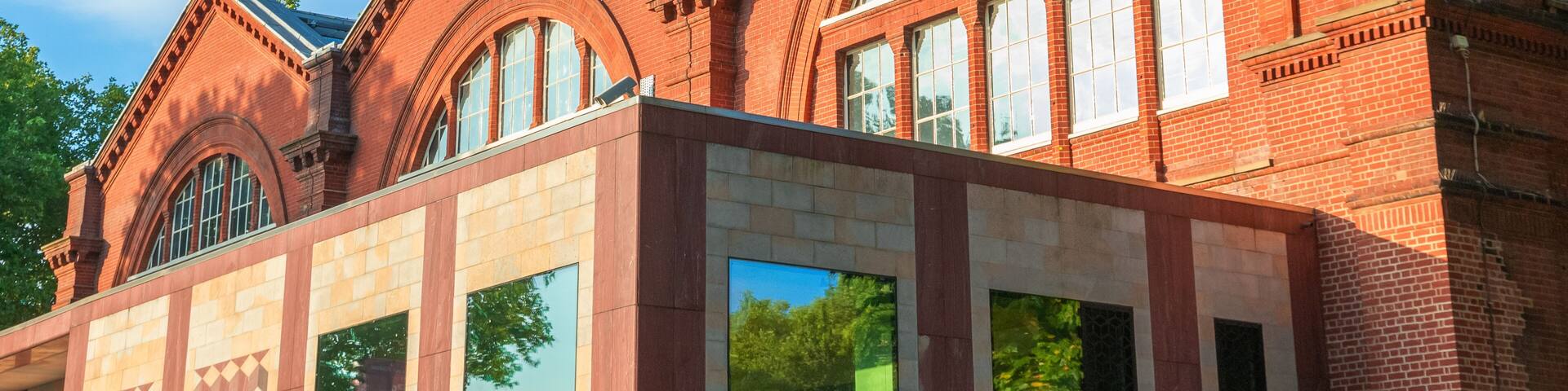 A red brick building with arched windows and a modern glass extension.