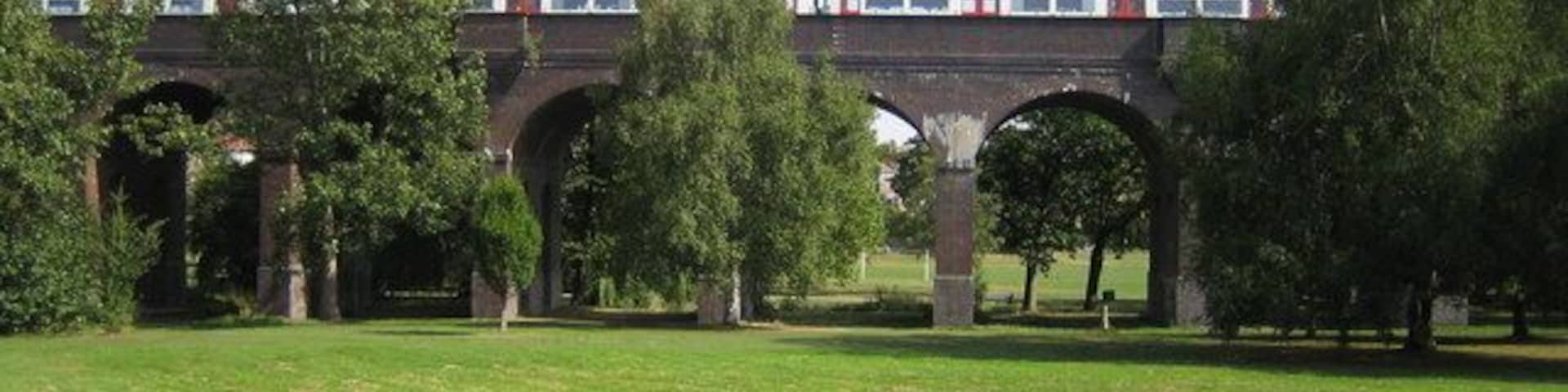 Arnos Park: Piccadilly Line viaduct. This viaduct carries the underground Piccadilly Line railway over the valley of Pymme's Brook. It was completed in 1933 when the line was extended beyond Arnos Grove station. A northbound train for the terminus at Cockfosters is crossing.