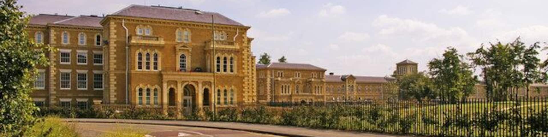 A large, historic building with a symmetrical facade and a paved road in front.
