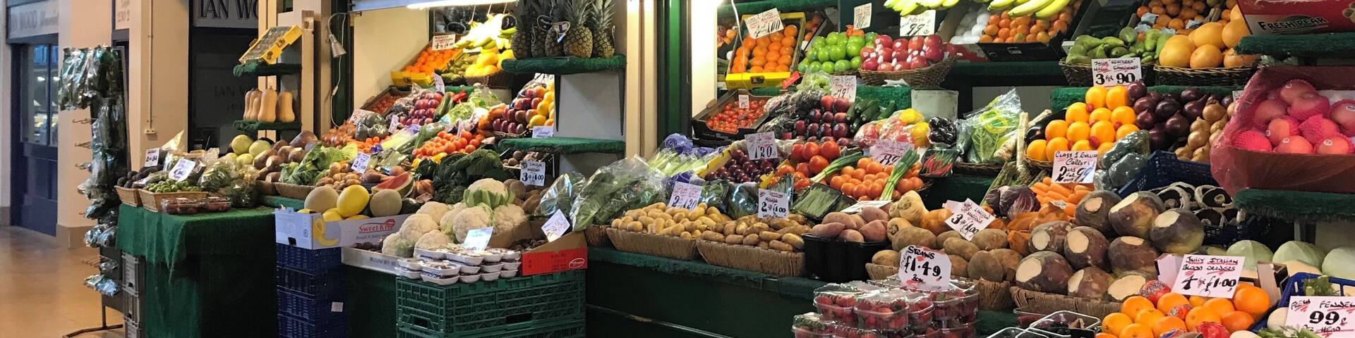A fruit and vegetable market stall with various produce on display.