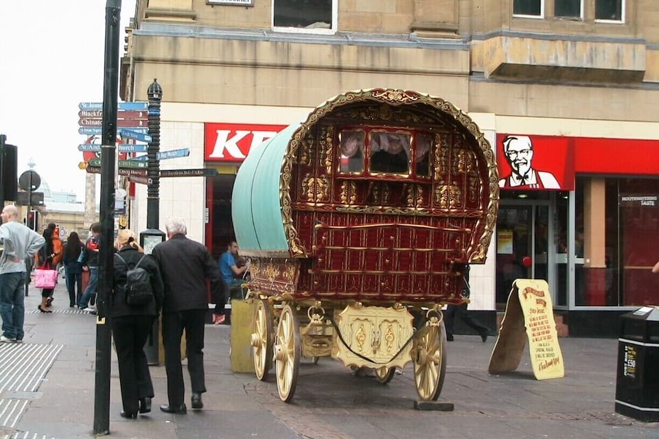 A gold and red ornate carriage parked on a city street.