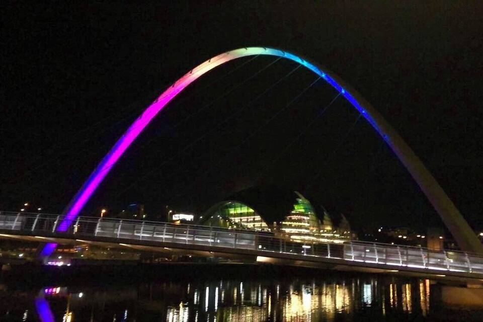 Eine Brücke mit einem Regenbogenbogen bei Nacht.