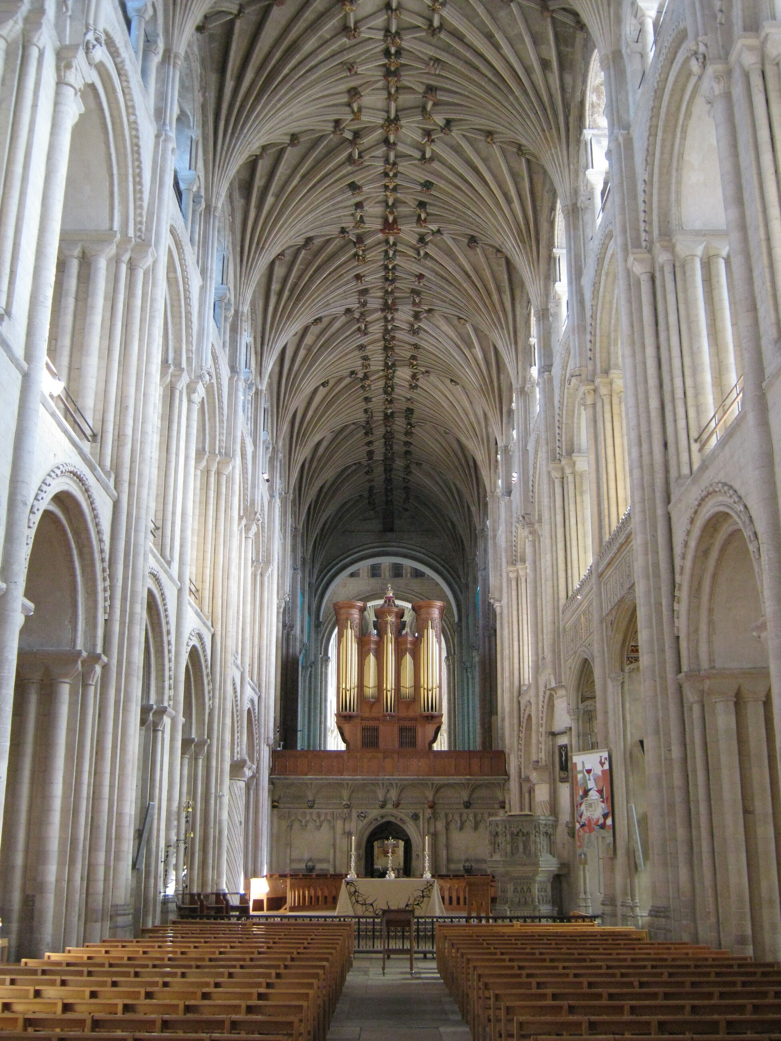 A cathedral interior with high vaulted ceilings, arched windows, and a central organ.