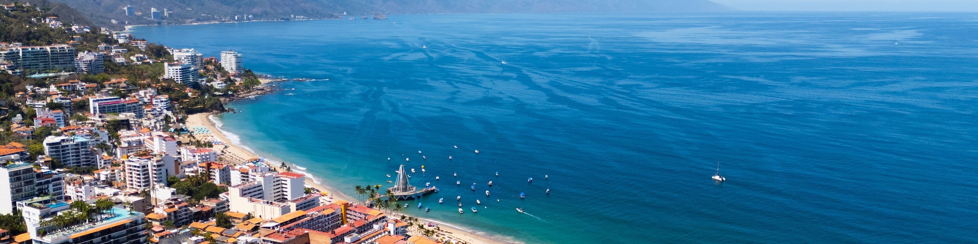 Uma cidade costeira com praia, edifícios e um mar azul cristalino.